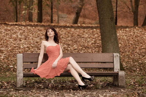 Mode jonge vrouw in rode jurk ontspannen in park — Stockfoto