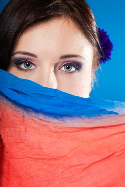 Woman hides her face with shawl on blue — Stock Photo, Image