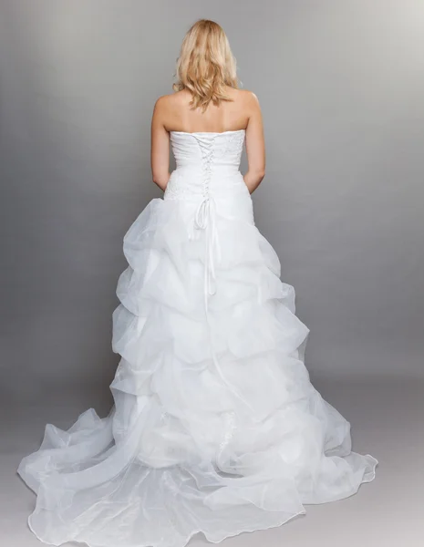 Prohlédni blond nevěsta bílé dlouhé svatební šaty zpět na šedé — Stock fotografie