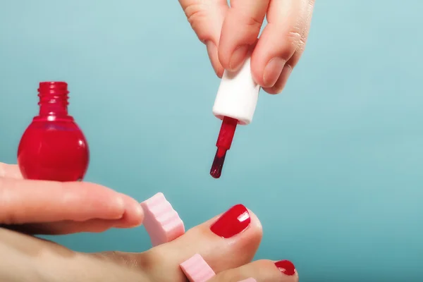 Voetpedicure aanbrengen van rode teennagels op blauw — Stockfoto