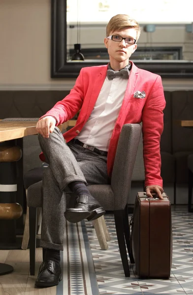 Młody przystojny stylowy mężczyzna z walizką czeka — Zdjęcie stockowe