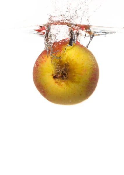 Gelber Apfel im Wasser spritzt über weißen — Stockfoto