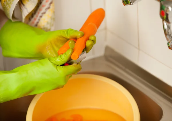 Vrouw handen snijden wortelen in de keuken. Gezonde voeding — Stockfoto