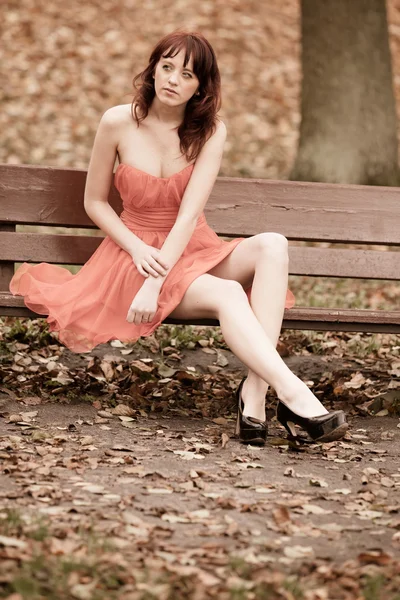 Moda jovem mulher em vestido vermelho relaxante no parque — Fotografia de Stock