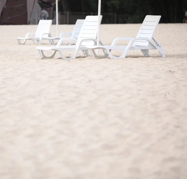 Chaises de piscine blanches sur la plage de sable — Photo