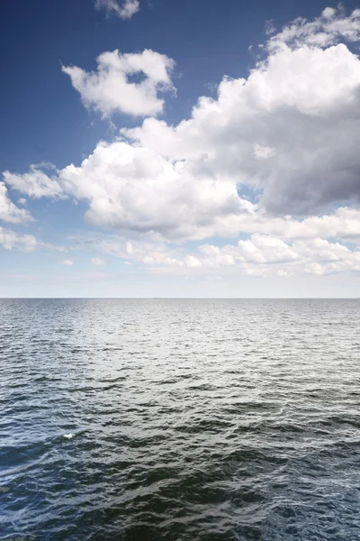 Cloudy blue sky above a surface of the sea — Stock Photo, Image