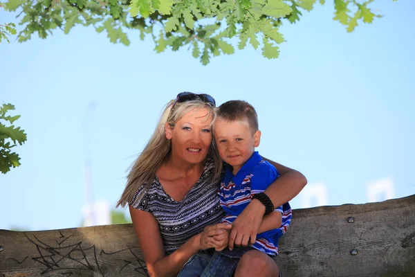 Feliz familia madre e hijo en el banco en el parque — Foto de Stock