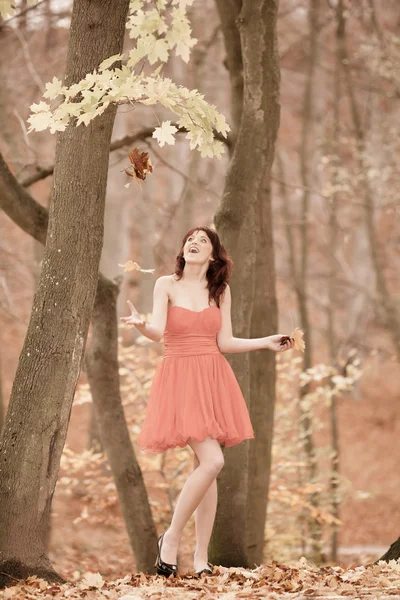 轻松玩的年轻女子树叶在秋天公园 — 图库照片