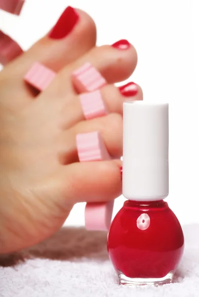 Pedicure del piede applicando unghie rosse su bianco — Foto Stock