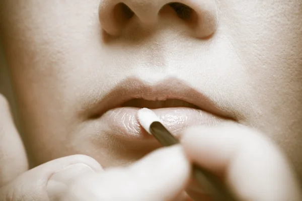 Makeup. flicka om läppglans läppstift på läpparna. del av ansiktet. sepia. — Stockfoto