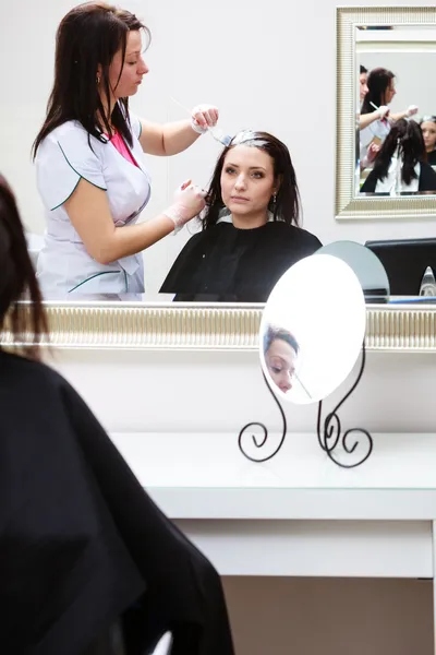 Парикмахер применяет цвет женщины клиента в салоне, делает краску для волос — стоковое фото