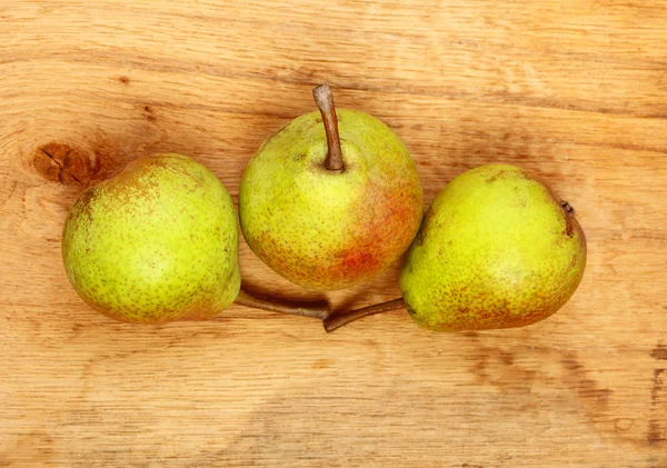 Trzy gruszki owoce na drewnianym stole — Zdjęcie stockowe