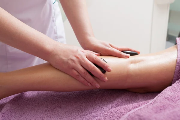 Salão de Spa. Pernas femininas com massagem de pedra quente. Cuidados com o corpo e relaxar . — Fotografia de Stock