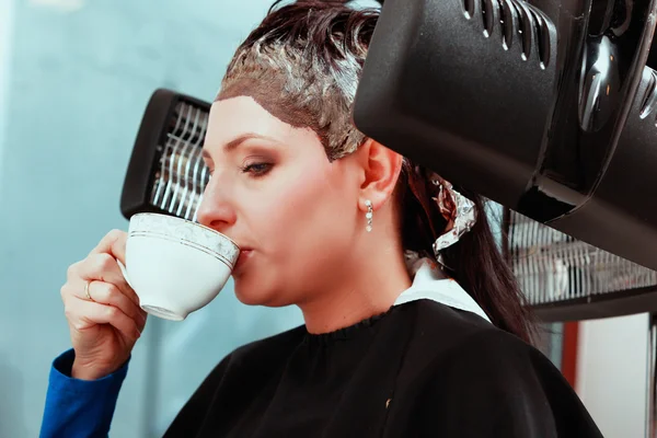 Woman drinking coffee tea in hair beauty salon. By hairdresser. — Stock Photo, Image