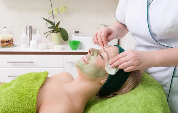 Salão de beleza. Cosmetician removendo máscara facial do rosto da mulher . — Fotografia de Stock