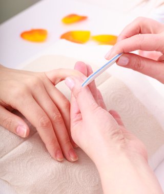 Beautician with file filing nails female client. Woman spa beauty salon clipart