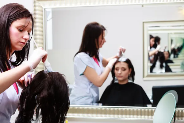 Coiffeur appliquant la couleur client féminin au salon, faire de la teinture capillaire — Photo