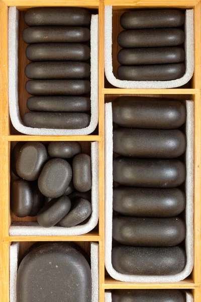 Pedras de massagem zen spa preto em caixa de madeira como fundo — Fotografia de Stock