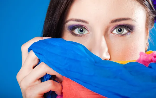 Woman hides her face with shawl on blue — Stock Photo, Image