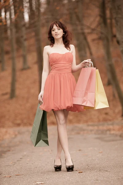 Elegante shopper vrouw lopen in park na het winkelen — Stockfoto