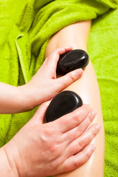 Beauty salon. Woman getting spa hot stone legs massage — Stock Photo, Image