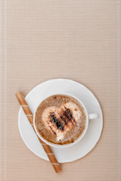 Weiße Tasse Kaffee und Waffelrolle mit Sahne auf braunem Hintergrund — Stockfoto