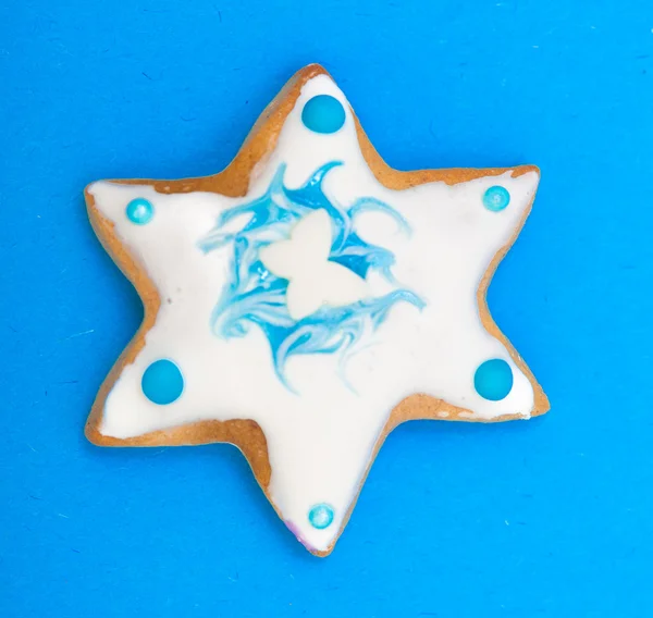 Christmas gingerbread cake star with icing and decoration on blue — Stock Photo, Image