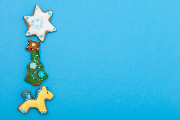 Gingerbread cake pony christmas tree star with icing decoration on blue — Stock Photo, Image