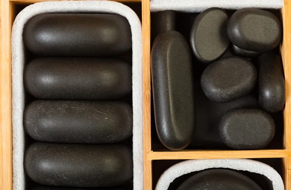 Piedras de masaje zen spa negro en caja de madera como fondo —  Fotos de Stock