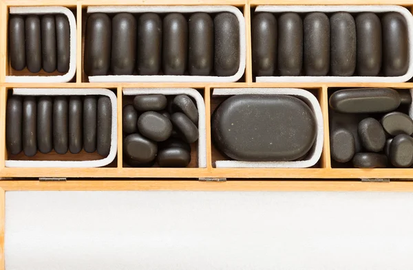 Zwarte spa zen massage stenen in houten koffer blanco kopieerruimte — Stockfoto