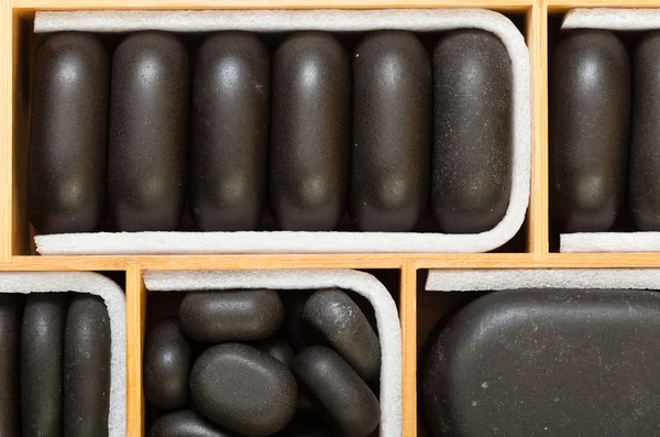 Piedras de masaje zen spa negro en caja de madera como fondo —  Fotos de Stock