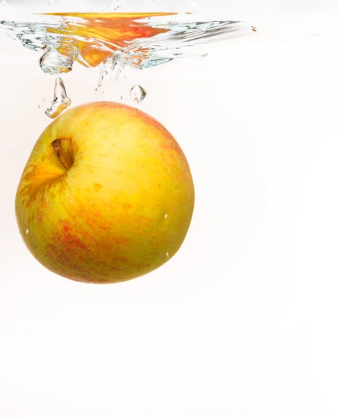 Žluté jablko v stříkající vodě nad bílá — Stock fotografie