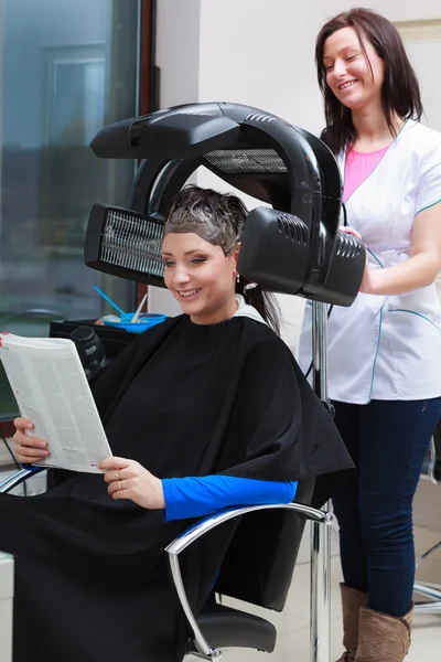 Woman reading magazine in hair beauty salon. By hairdresser. — Stock Photo, Image