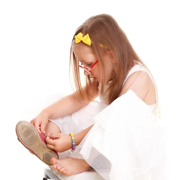 Criança menina tenta colocar em seus sapatos isolados — Fotografia de Stock