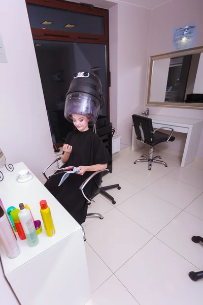 Mulher rolos de cabelo encrespadores leitura revista secador de cabelo salão de beleza — Fotografia de Stock