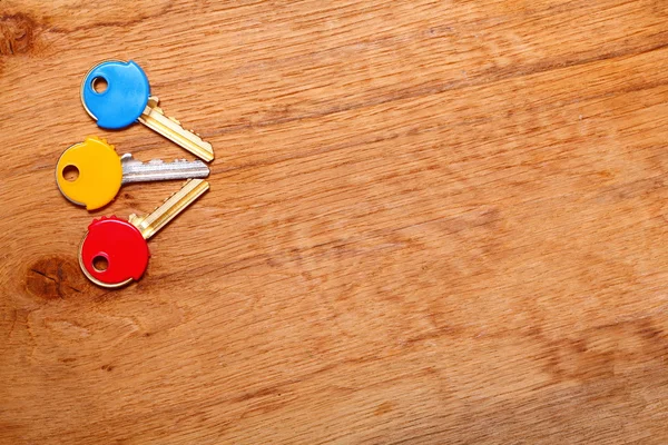 Klíče od domu s barevnými plasty kabáty čepice na stole — Stock fotografie