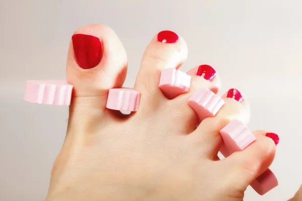 Pedicura del pie aplicando uñas de los pies rojas — Foto de Stock