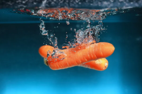 Carrot in the water splash over blue