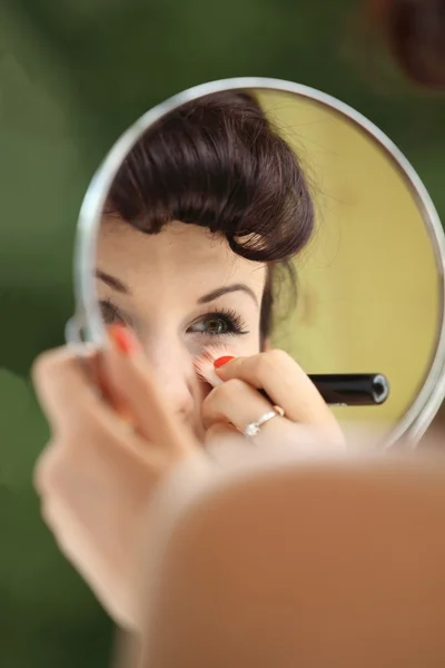 Mädchen im Retro-Stil schminken Blick auf Spiegel drinnen — Stockfoto