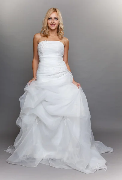 美丽的金发新娘白色的长婚纱礼服在灰色 — 图库照片
