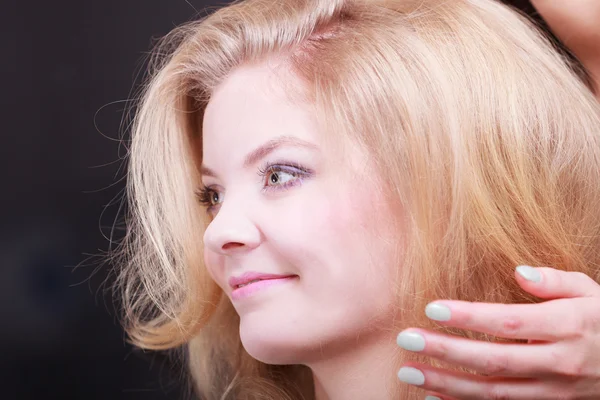 Menina sorridente bonita com cabelo ondulado loiro por cabeleireiro no salão de beleza — Fotografia de Stock