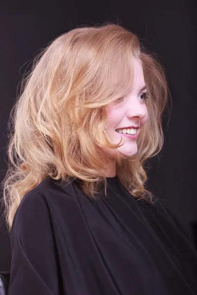 Beautiful smiling girl with blond wavy hair by hairdresser in beauty salon — Stock Photo, Image