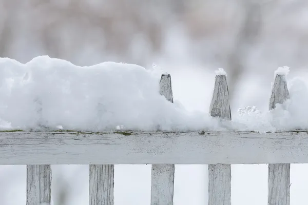 Old white wooden fence covered with snow. Winter seasonal specific.