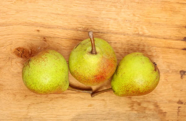 Trzy gruszki owoce na tle drewniany stół — Zdjęcie stockowe