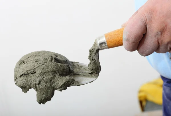 Mão segurando uma espátula de balde com argamassa de cimento — Fotografia de Stock