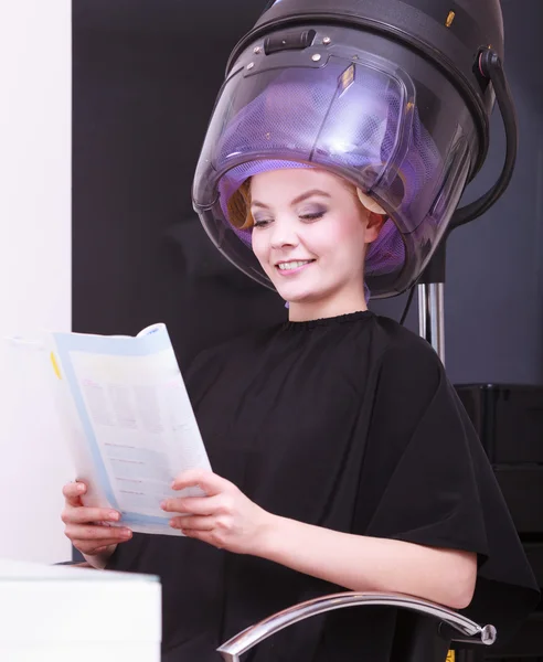 Girl relaxing reading magazine hairdryer by hairstylist in hair beauty salon — Stock Photo, Image