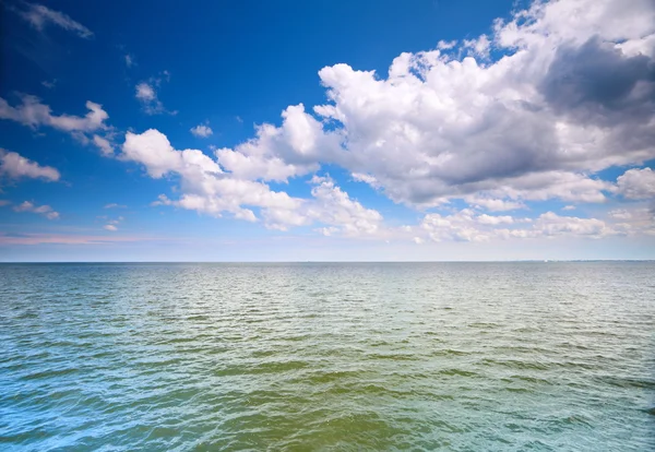 Cielo azzurro nuvoloso sopra una superficie del mare — Foto Stock