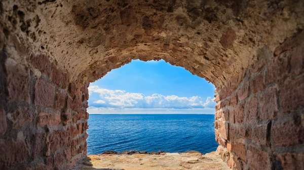 View of blue sea seascape from hole window frame in old stone wall — Stock Photo, Image