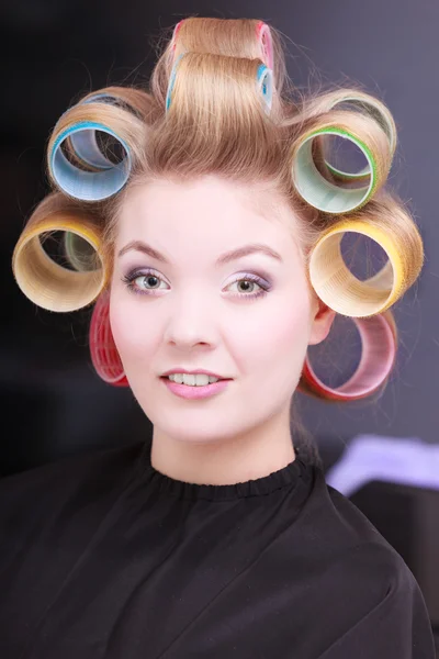 Happy blond girl hair curlers rollers by haidresser in beauty salon — Stock Photo, Image