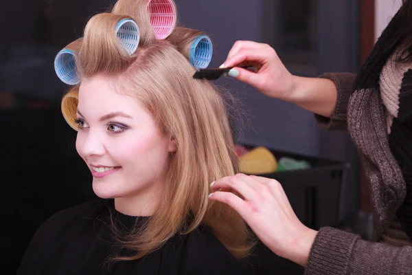 Blond meisje haar krulspelden rollen door Kapper — Stockfoto